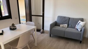 Un salon moderne avec un canapé gris, une table blanche et une chaise blanche.