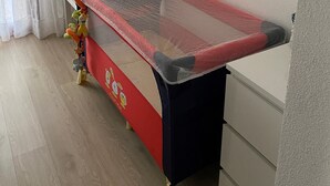 Un parc pour enfants avec des jouets, un cintre en métal et une bibliothèque remplie de livres.
