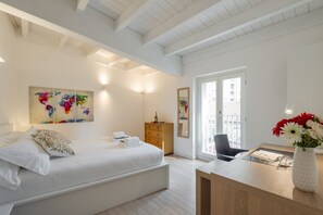 Ein modernes Schlafzimmer mit einem Bett, einer Holzkommode, einem Schreibtisch mit Blumen in einer Vase und einem Wandbild einer Weltkarte.