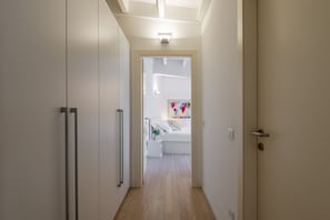 A hallway leading to a bedroom with a bed, a nightstand, and a wall-mounted light fixture. - UMBRIA, 120 - Cozy and well-connected (Milano)