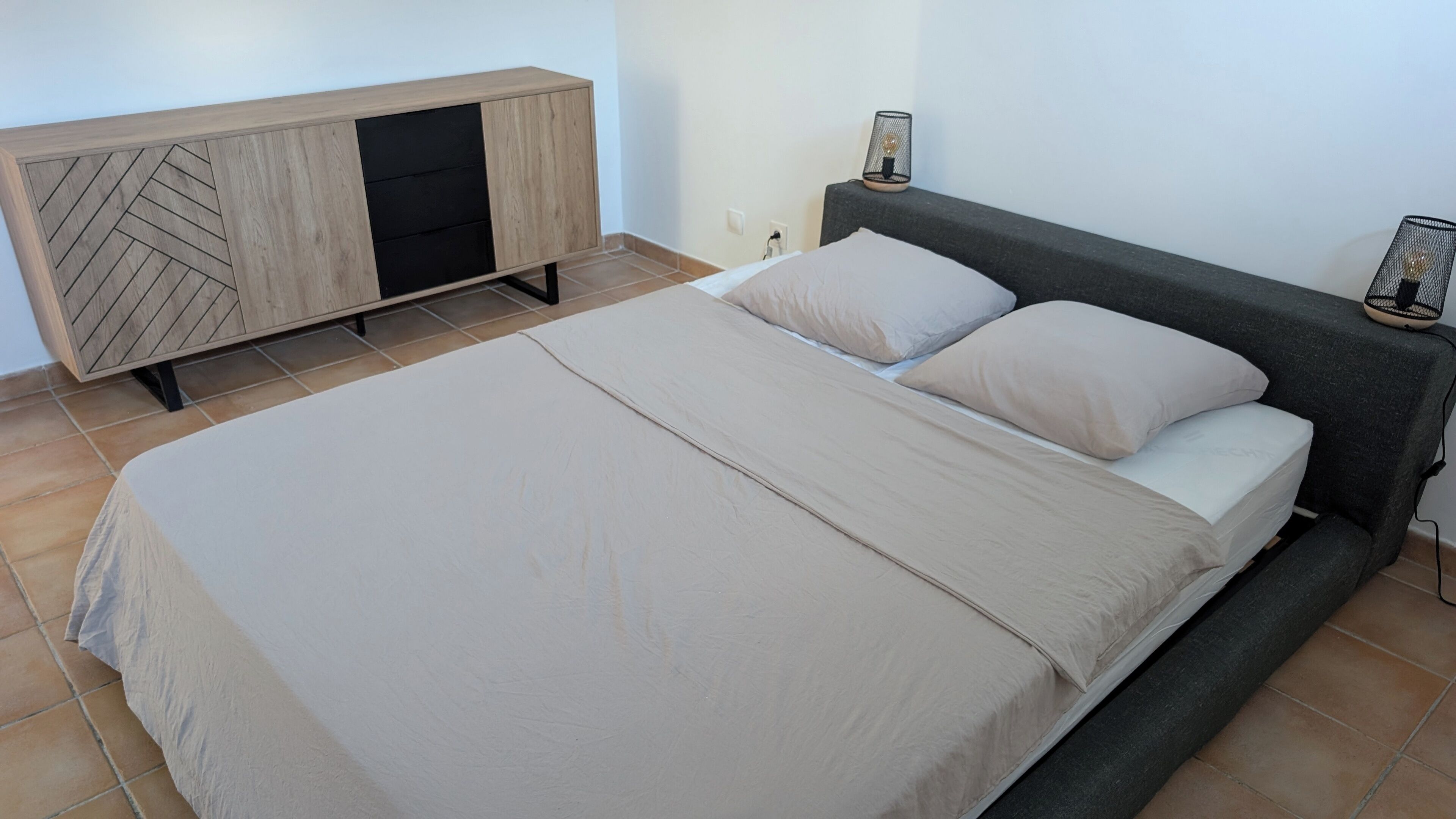 A bedroom with a bed, a wooden cabinet, and a nightstand.
