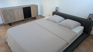A bedroom with a bed, a wooden cabinet, and a nightstand. - Ocean view appartement up to one of the most beautiful beach of the island (Le Gosier)
