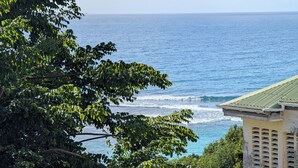 A coastal view with a building featuring a green roof and a balcony. - Ocean view appartement up to one of the most beautiful beach of the island (Le Gosier)