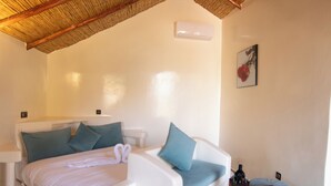 A modern bedroom with a curved bed, a small ottoman, a side table, and a ceiling fan. - Bungalow Nature & Bien-Être near Marrakech | Swimming pool, Hammam & Tranquility (Marrakech)