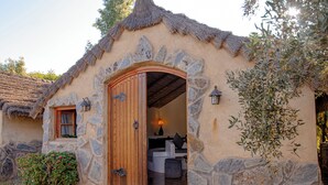 A rustic stone building with a wooden door, a small window, and a thatched roof. - Bungalow Nature & Bien-Être near Marrakech | Swimming pool, Hammam & Tranquility (Marrakech)
