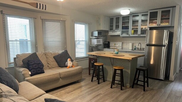 A compact living space with a kitchenette, a sofa, a coffee table, and a small bar area. - Peaceful 2-bedroom condo in Wildwood Crest, close to beach (Wildwood)