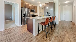 A modern kitchen with stainless steel appliances, a granite countertop, and wooden flooring. - Spacious 1-BR, 2-King Beds, Near Mayo, Pool, Gym, Fast Wifi Workspace, Beach (Jacksonville)