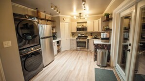 A modern kitchen with stainless steel appliances, wooden flooring, and a built-in oven. - Soak Under the Stars - Hot Tub, AC, Downtown Bungalow (Flagstaff)