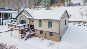 A two-story building with a balcony, a covered porch, and a snow-covered landscape.