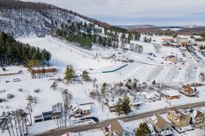 A snow-covered ski resort with a ski lift, buildings, and a parking area. - New! Modern Lakeview Ski Retreat w/ Hot Tub (McHenry)