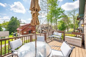 Eine Holzterrasse mit Sitzgelegenheit, einem Tisch und einem großen Sonnenschirm.