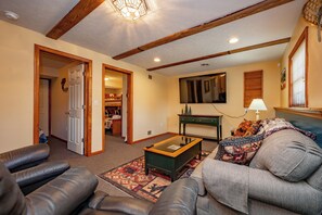 A living room with a coffee table, sofa, and a television. - New! Modern Lakeview Ski Retreat w/ Hot Tub (McHenry)