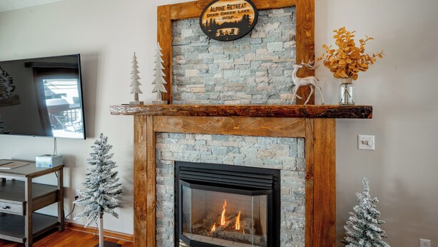 A fireplace with a stone surround, a sign above it, and two small Christmas trees on either side.
