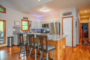 A kitchen with a granite countertop, stainless steel appliances, and wooden cabinetry. - New! Modern Lakeview Ski Retreat w/ Hot Tub (McHenry)