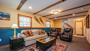 A living room with a sofa, two armchairs, a coffee table, a rug, and a staircase.