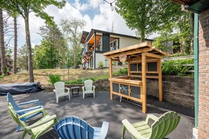 An outdoor patio area with Adirondack chairs, a wooden pergola, and a small table. - New! Modern Lakeview Ski Retreat w/ Hot Tub (McHenry)