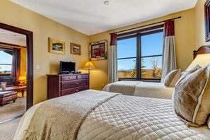 Une chambre d’hôtel avec deux lits, une télévision, une commode et une grande fenêtre donnant sur l’extérieur.
