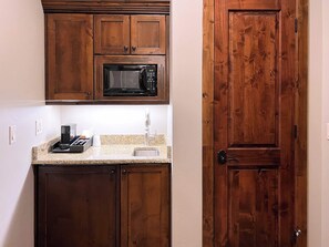 A compact kitchen with wooden cabinets, a built-in microwave, a sink, and a coffee maker. - Sunrise Gondola Getaway - Ski In/ski Out (Park City)