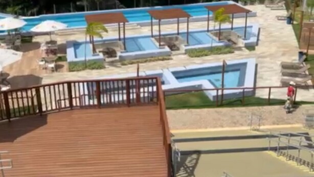 A resort with multiple swimming pools, palm trees, and a wooden deck. - Bright 2-bedroom apartment with AC in beautiful Natal -Cotovelo (Parnamirim)