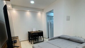 A modern bedroom with a bed, a TV, a desk, and a refrigerator. - Bright 2-bedroom apartment with AC in beautiful Natal -Cotovelo (Parnamirim)