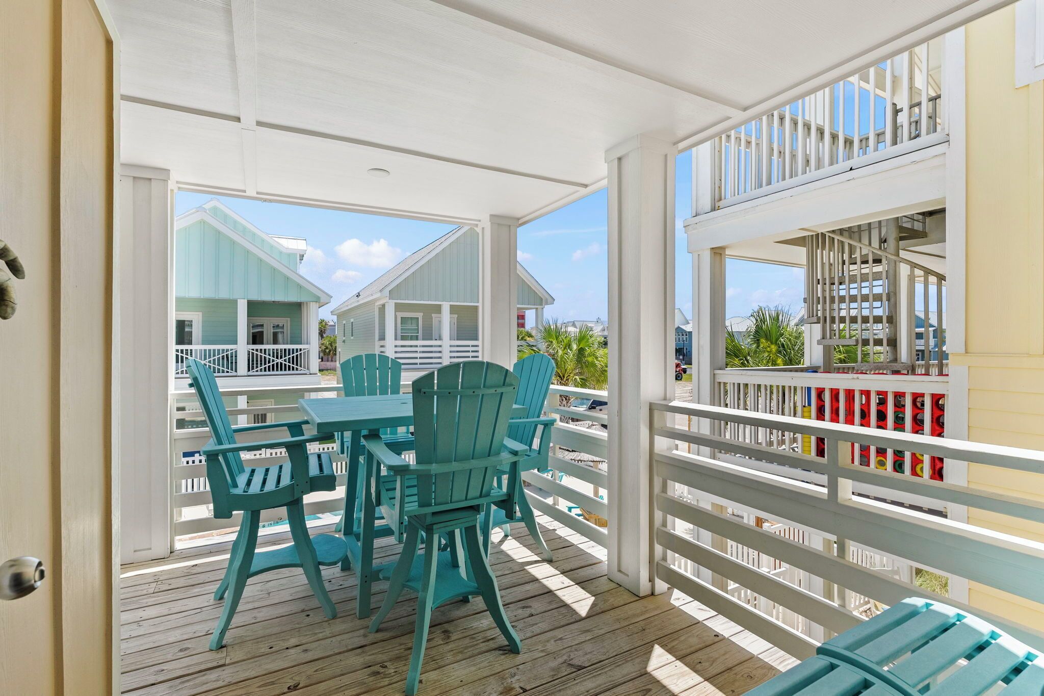 Un espace extérieur abrité, doté d’une terrasse en bois, d’une table avec des chaises et d’une vue sur les maisons voisines.