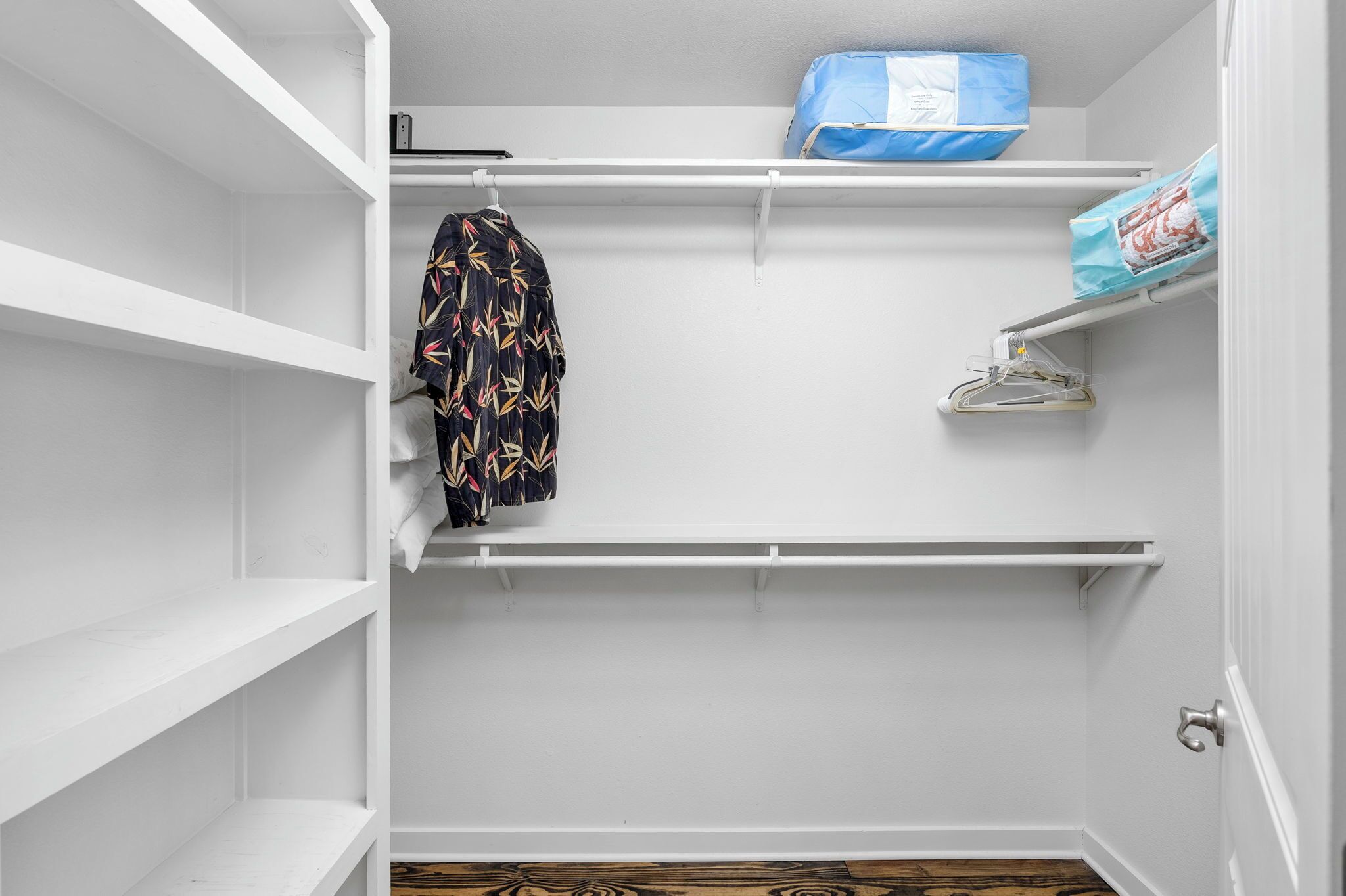Un armario blanco con repisas, una barra para colgar ropa y una puerta.