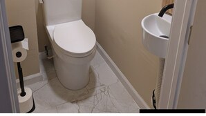 Une petite salle de bain avec des toilettes, un lavabo et un miroir.