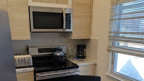 Eine kleine Küche mit Mikrowelle, Toaster, Herd und Kaffeemaschine.