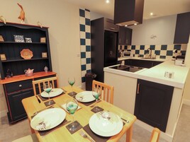 A compact kitchen with a dining area, featuring a microwave, stove, and a small refrigerator.