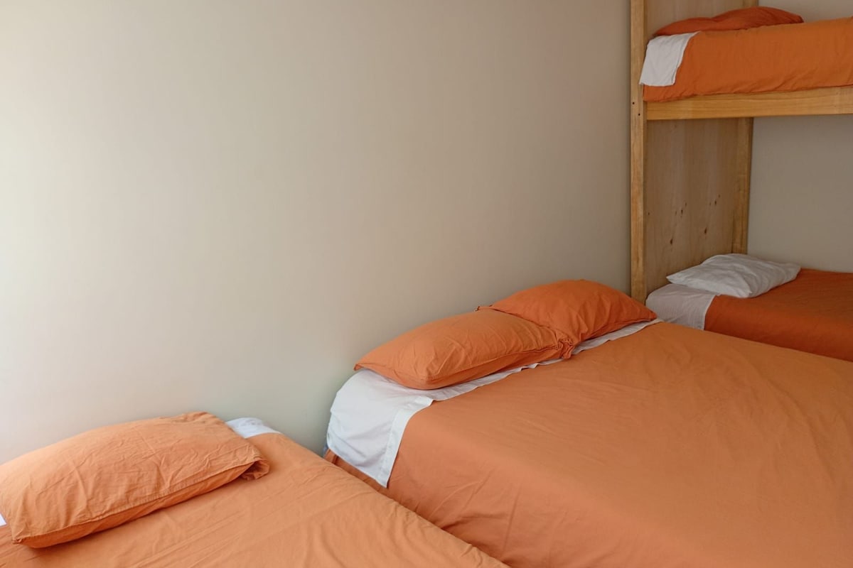 A room with two beds, each with orange bedding and pillows.
