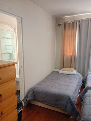 A bedroom with a single bed, a wooden dresser, and a glass cabinet. - Hostal Kahlo (Ciudad de México)