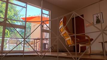 Una habitación con un ventanal grande, una silla y una puerta.