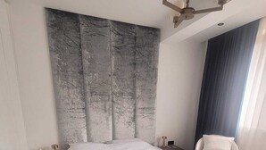 A modern bedroom with a large bed, a headboard with a textured design, a bedside table, a chair, and a window with curtains. - Soothing 1-bedroom apartment in awesome Kopaonik getaway (Kopaonik)