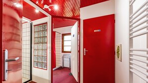 A corridor with red doors, a tiled wall, and a radiator. - Gîte de l'Ecluse for 10 Guests (Bassanne)