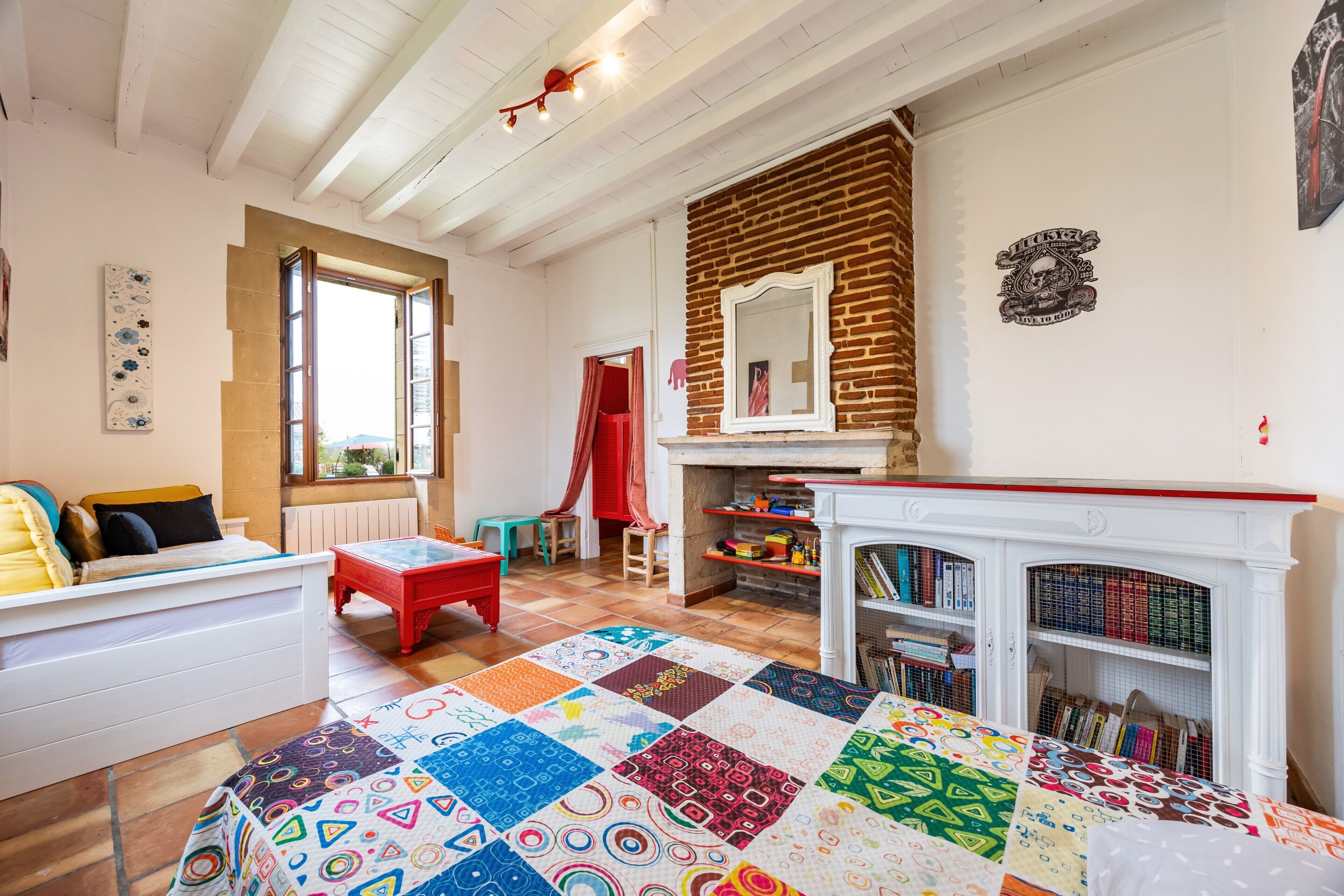 Una habitación amplia con una cama grande, una silla roja, una chimenea y una estantería.