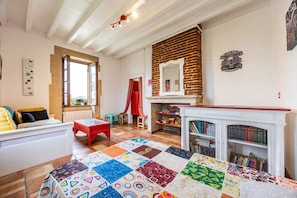 Een ruime kamer met een groot bed, een rode stoel, een haard en een boekenkast.