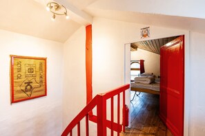 Een trap met rode leuningen die leidt naar een kamer met een bed en een raam.