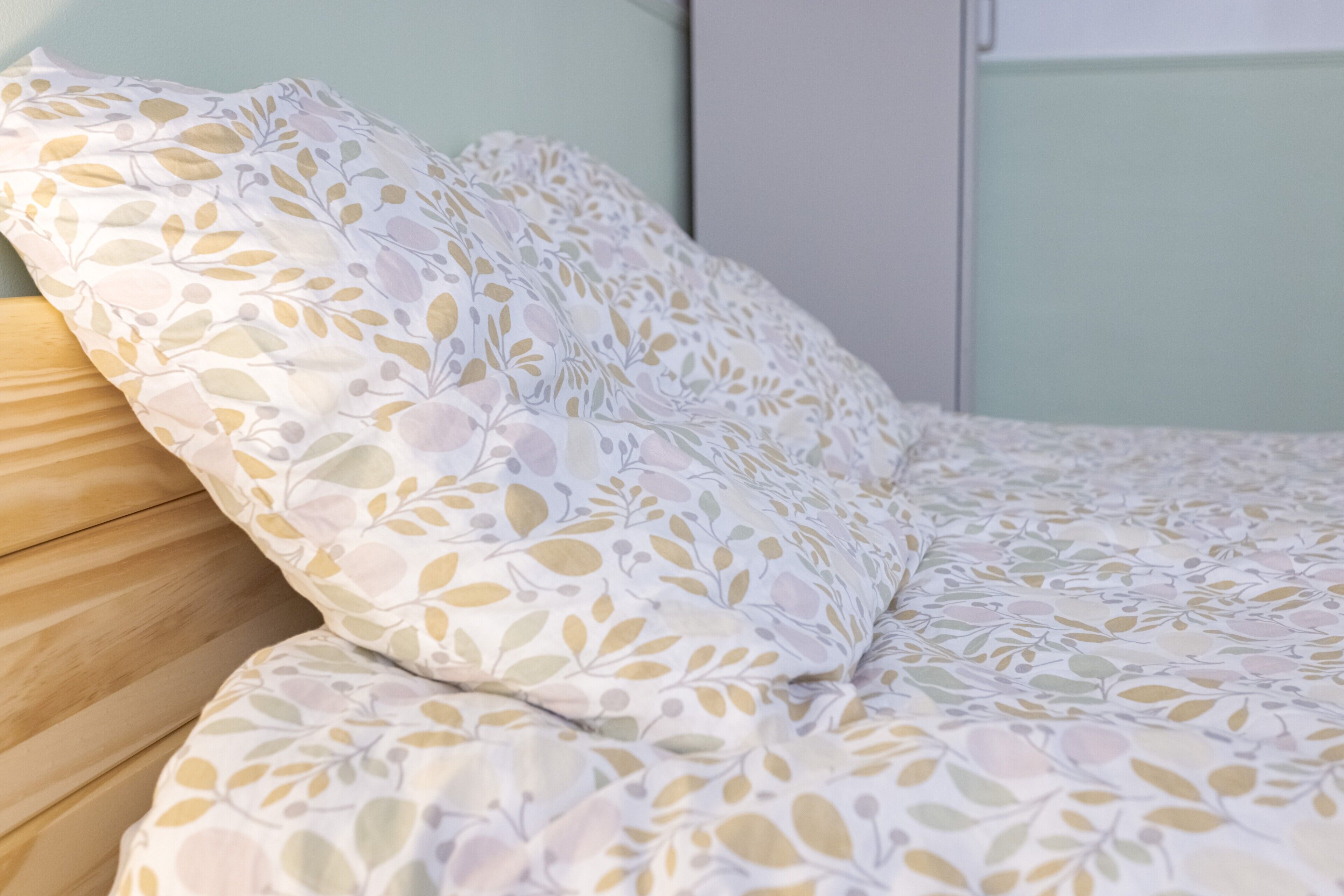A neatly made bed with a floral patterned bedspread and pillows.