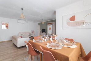 A dining room with a table set for six, chairs, a sofa, and a television in the background. - Le Carmen apartment in the heart of Saint-Hippolyte, 3 bedrooms, up to 6 guests (Saint-Hippolyte)