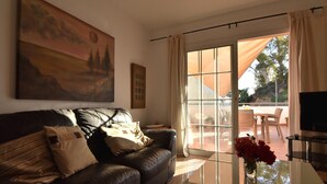 A living room with a leather sofa, a glass coffee table, and a painting on the wall. - Corinto Apartment, 100m from Burriana Beach (Nerja)