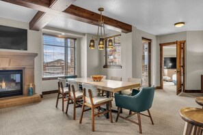 A dining area with a wooden table and chairs, a fireplace, and a view of the outside. - Sunrise Gondola Lodge - Ski-in/ski-out (Park City)