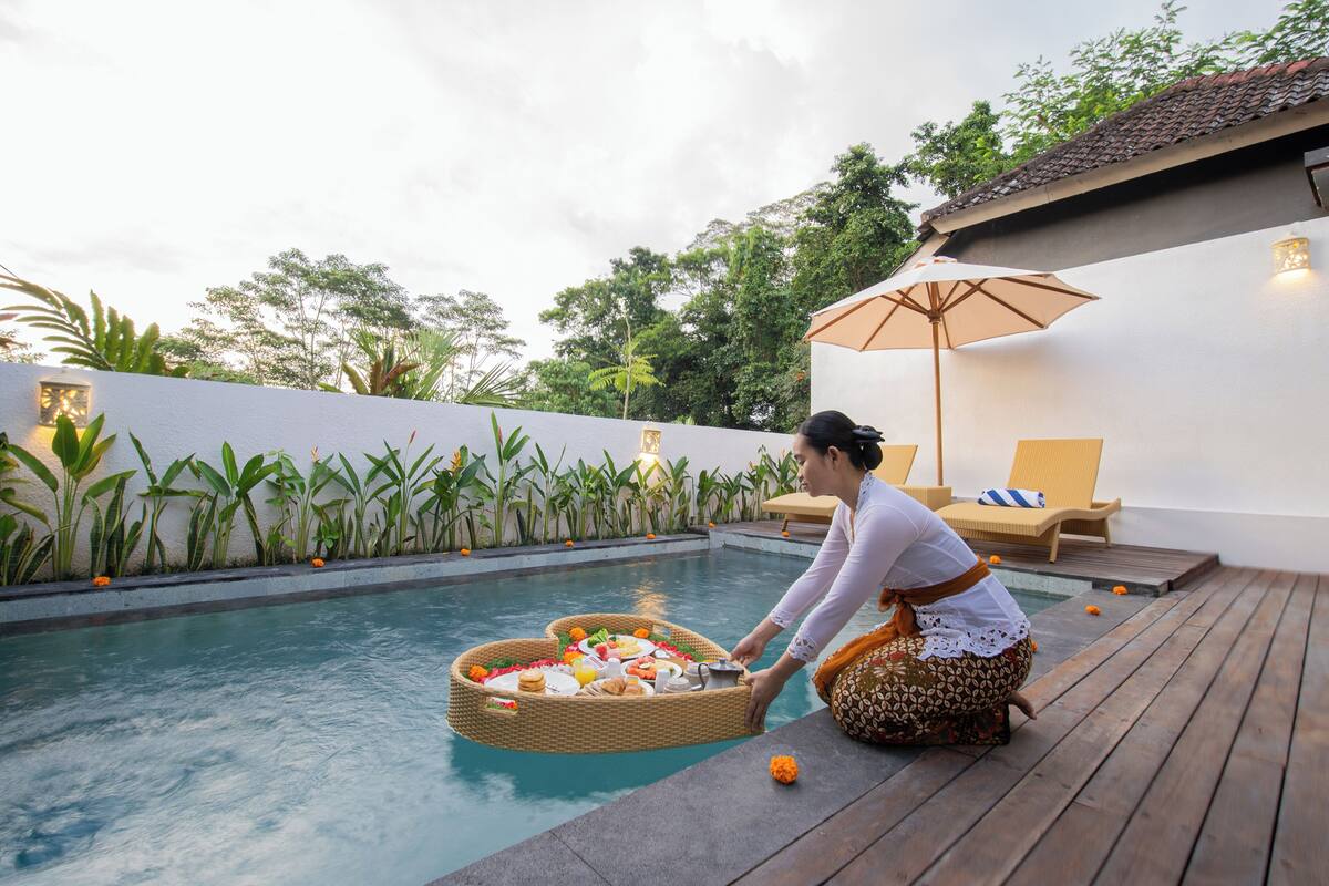 Un espace aménagé au bord de la piscine, avec un plateau flottant servant de table, une chaise longue et un mur végétalisé.