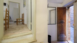 Eine Treppe führt zu einem Raum mit einer Holztür, einer weißen Wand und einem Fliesenboden.