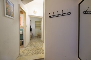 Un pasillo con piso de baldosas, un perchero y una puerta.