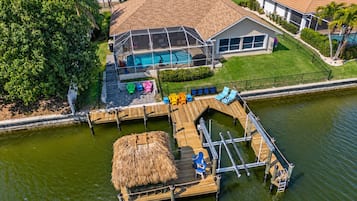 Une propriété située au bord de l’eau, dotée d’une piscine, d’un quai et d’une structure à toit de chaume.