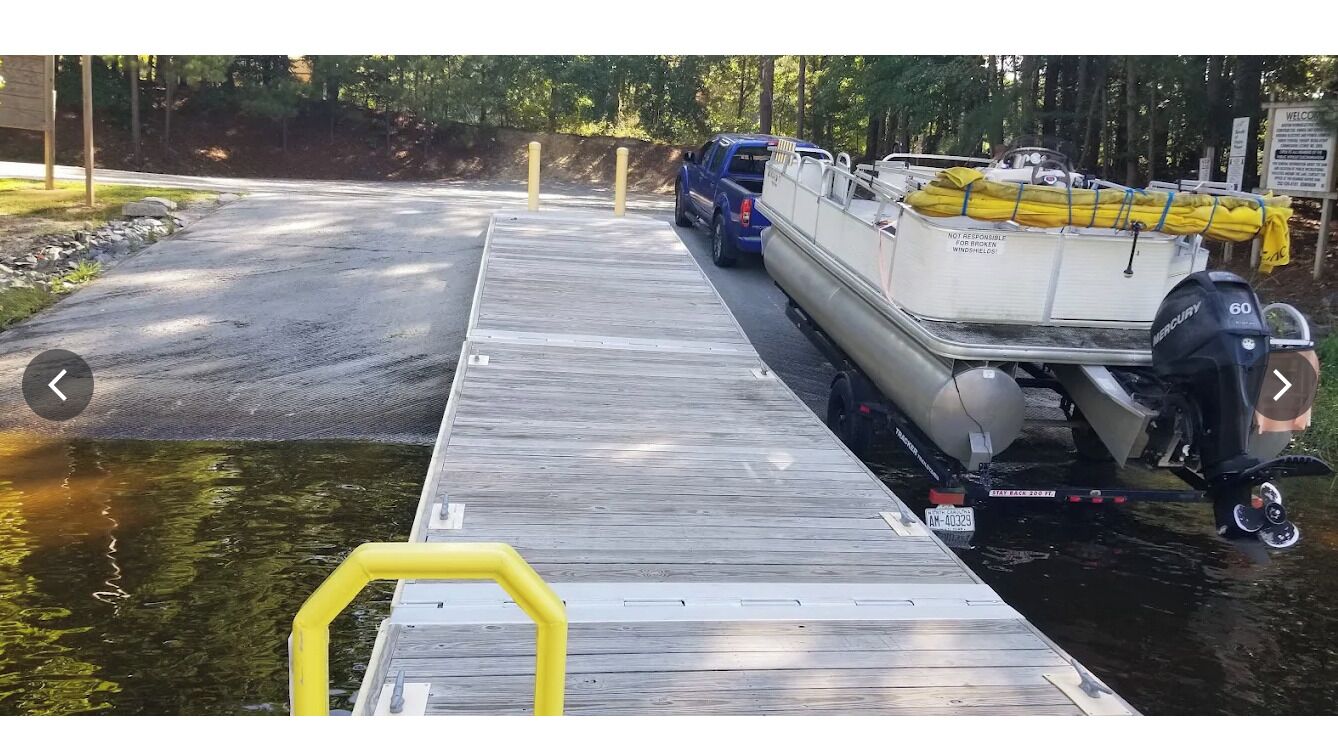 A dock with a boat, a blue vehicle, and a sign.