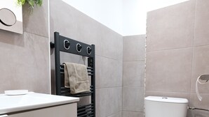 A modern bathroom with a white toilet, a black towel rack, and a white sink. - Romy's House (Thuir)