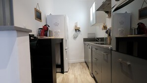 A modern kitchen with stainless steel appliances, a wooden floor, and a compact layout. - Romy's House (Thuir)
