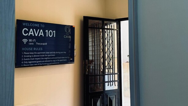 A hotel room with a bed, a sign with house rules, and a view of the outside. - Abdali elite studio (Amman)