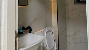 A bathroom with a toilet, sink, and mirror. - Abdali elite studio (Amman)